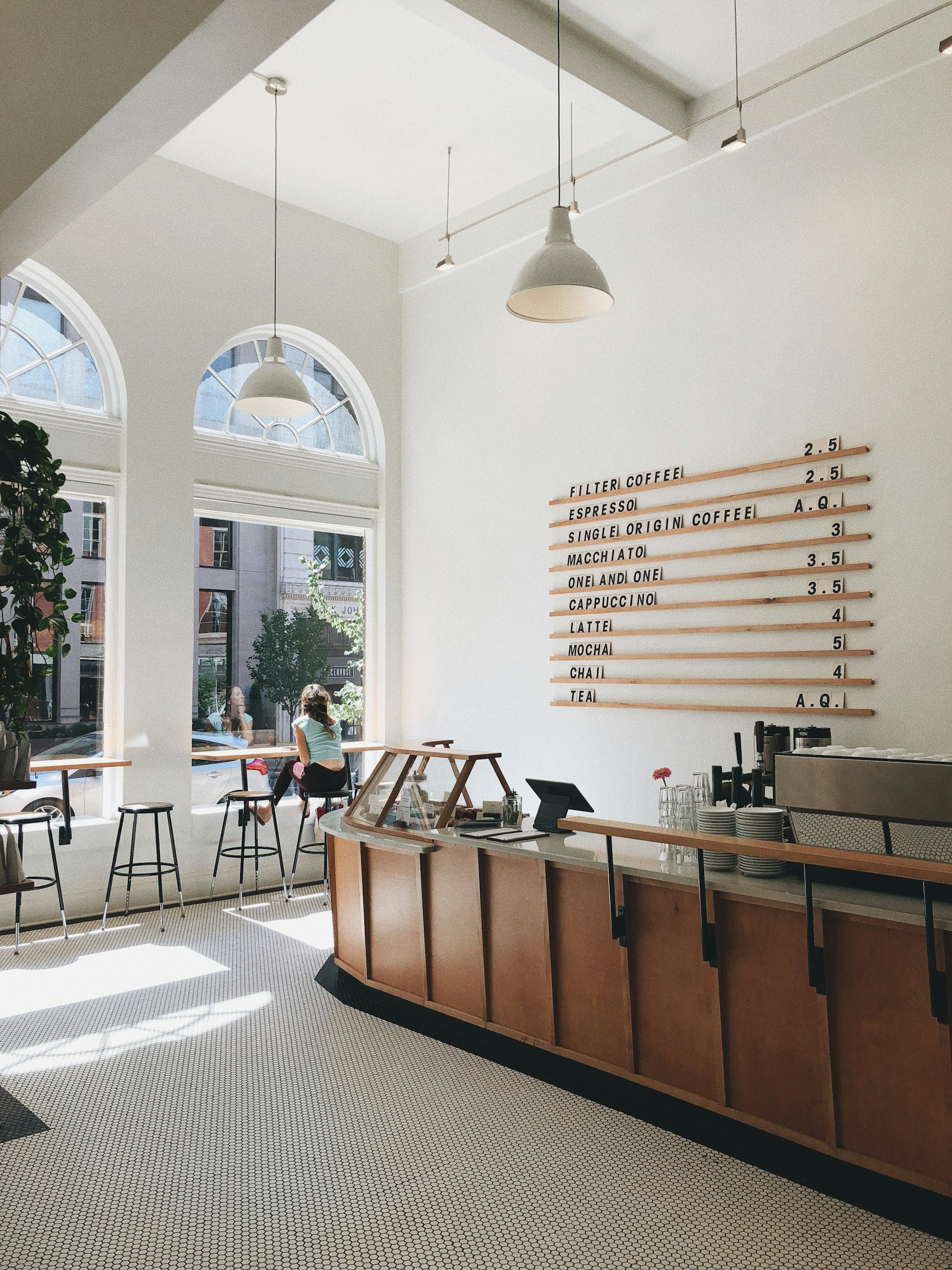Bright modern coffee shop with an arched window and wood counter